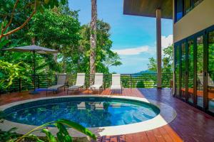 una piscina en una terraza con sillas y sombrilla en Casa Vista Verde, en Uvita