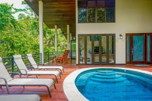 una piscina con tumbonas y una casa en Casa Vista Verde, en Uvita