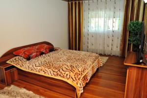 a bedroom with a bed with a leopard print blanket at Casa Cri și Ramo in Bradu