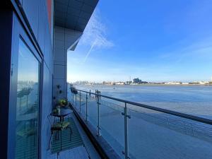 einen Balkon eines Gebäudes mit Blick auf das Wasser in der Unterkunft Snuggle Inn - Serviced apartments - Riverview's close to O2 Arena, London Excel, London City Airport and Woolwich Ferry with parking in London