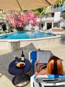 una mujer leyendo un libro en una mesa con una botella de vino en Villas Carela, en Cabarete