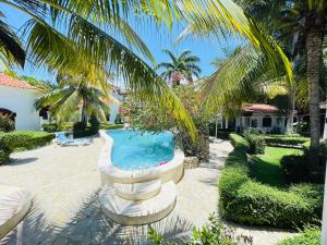 a swimming pool in a yard with a palm tree at Villas Carela, Villas Privadas con Piscina y Jacuzzi a 2 Minutos de la Playa de Cabarete in Cabarete