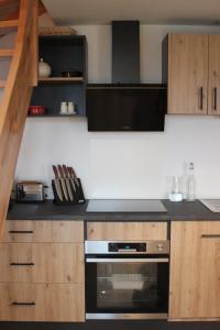 a kitchen with a stove and wooden cabinets at Beau duplex vue sur le Lac Blanc in Orbey