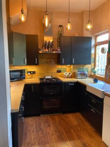 a kitchen with black cabinets and a stove top oven at Room with a view Catford, homestay in Hither Green