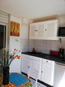 a kitchen with white cabinets and a sink and a chair at Appartement idéal famille, vue sur mer. in Le Moule