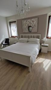 a bedroom with a large white bed and a chandelier at Sottocastello 1 in Gorizia