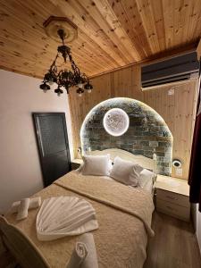a bedroom with a large bed with a stone wall at "Mani Guest House" in Gjirokastër