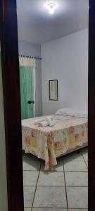 a bedroom with a large bed with a flowered blanket at Pouso da Praça in Bonfim