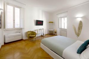 a white bedroom with a bed and a chair at Residenza al Colosseo in Rome