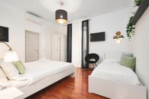 a white bedroom with two beds and a chair at Quiet Night Affittacamere La Spezia in La Spezia