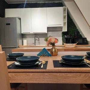 a kitchen with white cabinets and black plates on a table at PasteLove Studio Apartament Pastelowe blisko Suntago Deepspot Mszczonów in Mszczonów