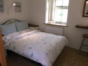 een slaapkamer met een bed met een paars dekbed en een raam bij new pottery in Penzance