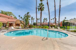 a swimming pool with chairs and palm trees at Palm Desert Home with Pool Access - Near Golfing! in Palm Desert
