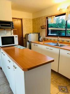 a kitchen with a counter top and a microwave at Preciosa Casa con Piscina y muelle en orilla Lago Rapel in Las Cabras