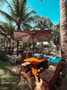 a table and chairs with an umbrella next to a pool at Village dos Pássaros in Belo Oriente