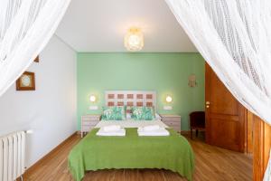 A Casa da Carminha في Pereiro de Aguiar: غرفة نوم خضراء مع سرير وبطانية خضراء