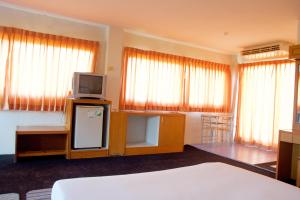 Habitación con cama y nevera con TV. en Sichang Shine Khao Resort, en Koh Sichang
