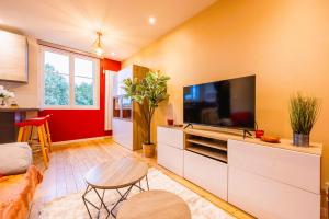 ein Wohnzimmer mit Flachbildfernseher und Tisch in der Unterkunft Appartement de standing - coeur de Rezé / 10min de Nantes in Rezé