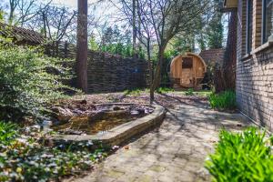 um quintal com uma banheira para pássaros e uma cerca em Wellnesshuis met jacuzzi en sauna in het bos em Lunteren