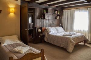 a bedroom with two beds and a window at Hostería La Posta Del Cazador in San Martín de los Andes