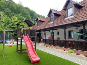 a playground in a house with a red slide at HUTA-TÚRA 42 Vendégház in Háromhuta