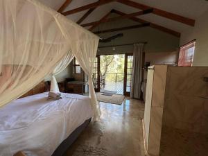 a bedroom with a bed with a mosquito net at Tree Symphony in Marloth Park