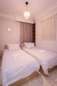two beds in a room with white sheets at Stylish apt w Jacuzzi, 10 min to White Tower in Thessaloniki