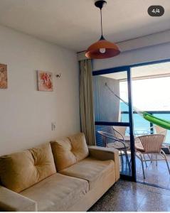 uma sala de estar com um sofá e uma grande janela em Iracema Flat residence em Fortaleza