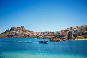 a boat in a body of water with houses on a hill at City Center near the beach in Castelsardo