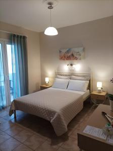 a bedroom with a large white bed with two lamps at Studios Antoniou in Skala