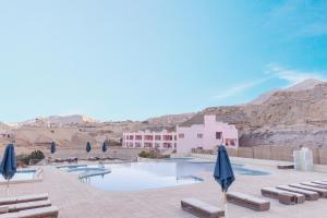 a pool with umbrellas and chairs and a building at La Siesta Hotel Al Sokhna in Ain Sokhna