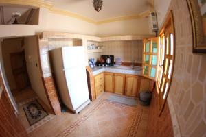 cocina con nevera blanca y armarios de madera en Tayafut ApartmentTerrace, en Mirleft