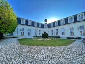 a large white building with a clock tower at Hotel Beauvilliers in Saint-Aignan