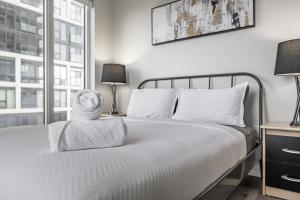 a bedroom with a bed with white sheets and a window at Toronto Garden Apartments in Toronto