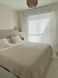 um quarto branco com uma cama grande e uma janela em Casa Bendita - LUXURY APARTMENT BENIDORM em Benidorm