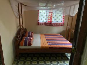 ナングウィにあるVillage Hostelの窓付きのベッドルームの小さなベッド1台