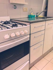 La cocina está equipada con fogones blancos. en Dpto 1 dormitorio, 3 cuadras del Rio y de las Peatonales!, en Rosario