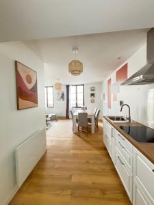 a kitchen with white cabinets and a dining room at Le Duplex Safari in Saint-Aignan