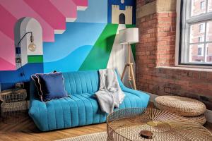 a living room with a blue couch and a colorful wall at I Should Cocoa (York) - Seebohm in York