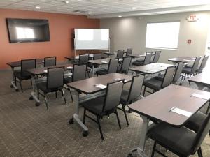 ein Klassenzimmer mit Tischen und Stühlen in einem Raum in der Unterkunft Candlewood Suites Fort Wayne - NW, an IHG Hotel in Fort Wayne