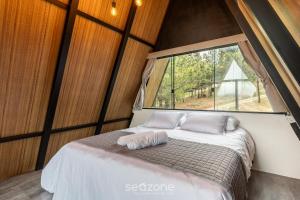 a bed in a room with a large window at Chales Naturale - Campos do Jordão - CNA in Campos do Jordão +52 photos