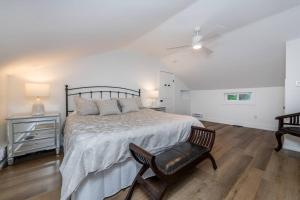 ein weißes Schlafzimmer mit einem Bett und einem Stuhl in der Unterkunft Gorgeous Muskokan Cottage on Six Mile Lake in Port Severn