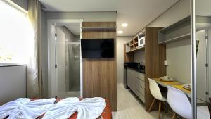 a bedroom with a bed and a desk and a kitchen at 07-STUDIO ENCANTADOR PARA CASAL in Curitiba