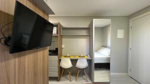 a room with a television and a small table with two chairs at 07-STUDIO ENCANTADOR PARA CASAL in Curitiba