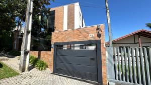uma porta de garagem preta numa casa de tijolos em 07-STUDIO ENCANTADOR PARA CASAL em Curitiba