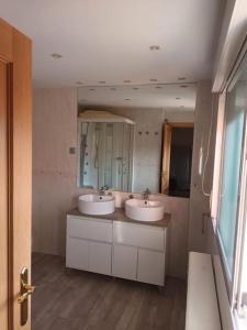 uma casa de banho com 2 lavatórios e um espelho em Precioso chalet de lujo em Boadilla del Monte