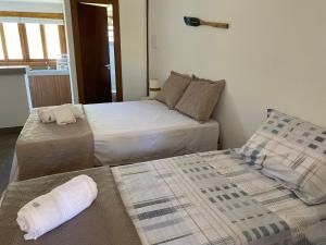 2 bedden in een kleine kamer met een nachtrok bij D'Ajuda Flat Taipu Bangalôs in Taipu