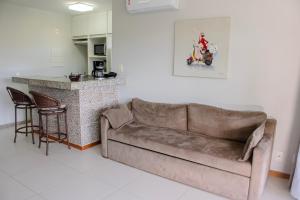 a living room with a brown couch and a kitchen at Imbassaí Apartments in Imbassai