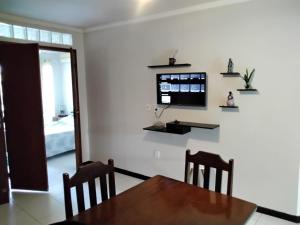 a dining room with a table and a television on a wall at Apt. aconchegante Melhor Localização do Centro: conforto e praticidade in Porto Seguro