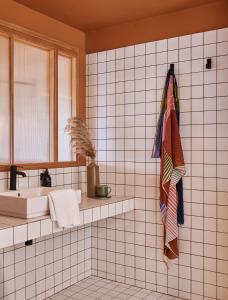 a white tiled bathroom with a sink and a mirror at Hôtel Oré, Saint-Malo in Saint Malo